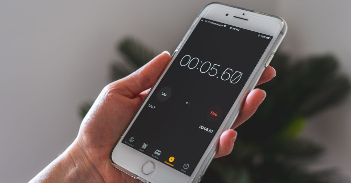 Close-up of a hand holding a smartphone with a stopwatch app running.